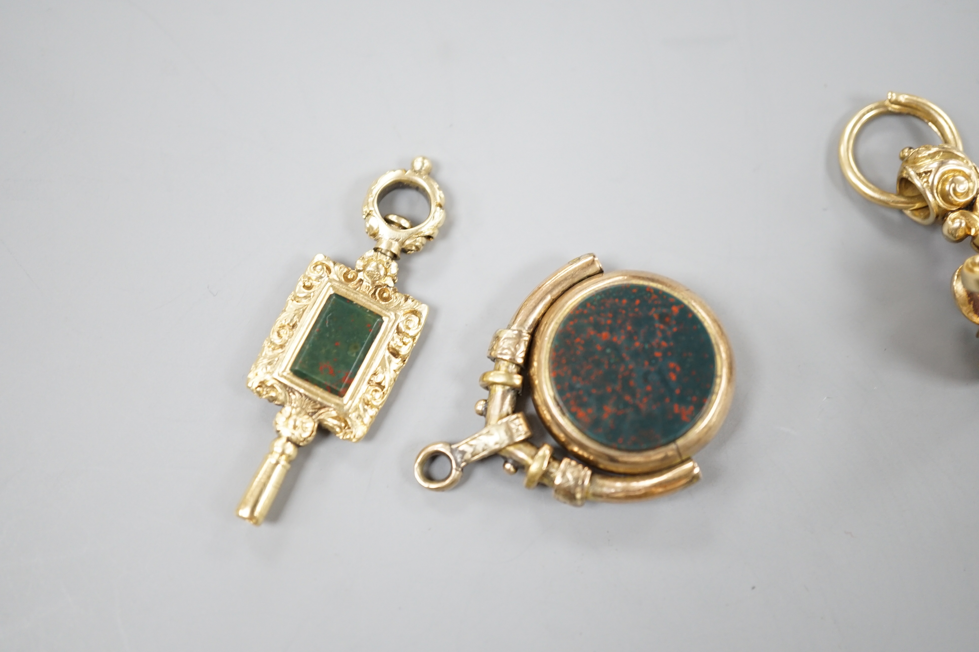 A 19th century yellow metal overlaid and foil backed gem set fob seal, 25mm, a similar chalcedony set spinning fob and a bloodstone set yellow metal overlaid watch key.